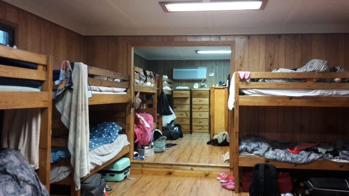 Bunk beds inside a woodem cabin. The beds are messy.