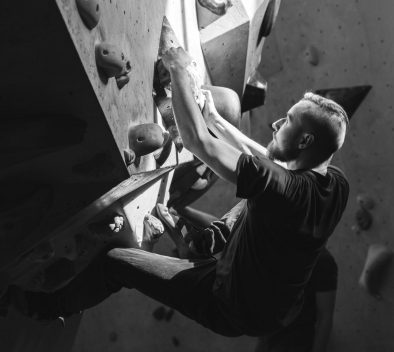 A black-and-white photo of a man bouldering.