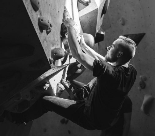 A black-and-white photo of a man bouldering.